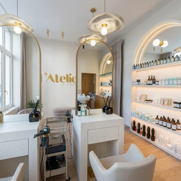 Intérieur d'un espace retail de luxe mettant en scène un agencement commercial haut de gamme : façade en bois noble poli avec panneaux et étagères intégrées présentant des produits de prestige, comptoir en matériaux nobles, ambiance lumineuse et épurée reflétant l'expertise en menuiserie sur mesure et les standards du luxe contemporain.